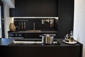 a kitchen with black cabinets and a pot on a stove at Conca9, Luxury attic with jacuzzi in Navigli in Milan +18 photos