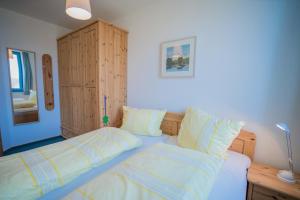 - une chambre dotée d'un lit avec des draps jaunes et blancs dans l'établissement Inselblume 14 - Blaue Ferienwohnung mit Balkon am Südstrand, à Burgtiefe auf Fehmarn 