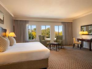 Una habitación de hotel con una cama, un escritorio y ventanas. en Mercure Hotel Windhoek, en Windhoek 85 fotos más
