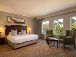 a hotel room with a bed and two chairs at Mercure Hotel Windhoek in Windhoek