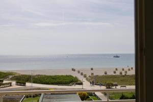 - une vue sur la plage avec un bateau dans l'eau dans l'établissement Inselblume 37 - Ferienwohnung mit Meerblick im Stranddistelweg 58, à Burgtiefe auf Fehmarn 