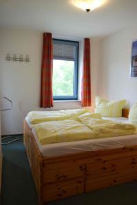 a large bed in a bedroom with a window at Inselblume 02 - Maritime Ferienwohnung, Blick zum Yachthafen in Burgtiefe auf Fehmarn 