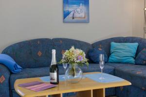 a blue couch with a bottle of wine and flowers on a table at Inselblume 39 - Komfortable Ferienwohnung mit Waschmaschine in Burg in Burg auf Fehmarn