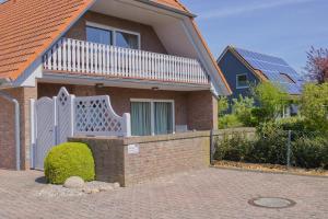 une maison avec une porte blanche et une clôture en briques dans l'établissement Inselblume 34 - Ferienwohnung mit Loggia, à Burg
