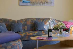 a living room with a couch and a table with a bottle of wine at Inselblume 38 - Zentrale Ferienwohnung in Burg mit Garten in Burg auf Fehmarn