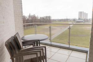 a balcony with a table and chairs and a view of a field at Inselblume 56 - Ferienwohnung am Südstrand mit Meerblick in Burgtiefe auf Fehmarn 