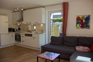 a living room with a couch and a kitchen at Inselblume 27 - Modernes Ferienhaus mit Garten in Burg in Burg auf Fehmarn