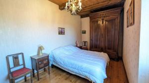 a bedroom with a bed and a chair and a chandelier at Gîte en pierre maison quercynoise in Vaylats