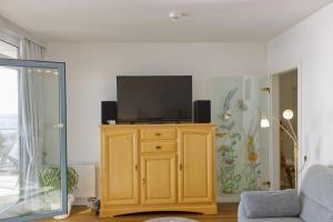 a living room with a television on a wooden cabinet at Inselblume 16 - Ferienwohnung mit Meerblick in der Strandburg B2.6 in Burgtiefe auf Fehmarn 