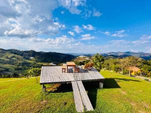 a wooden bench sitting on top of a green field at Chalés Terras Altas in Gonçalves