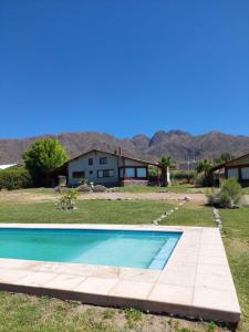a pool in front of a house with mountains in the background at Cabañas Altos de Nopal in Ciudad Lujan de Cuyo