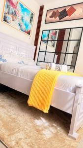 a bedroom with a bed with a yellow blanket on it at Sana Homes in Kampala