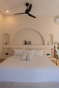 a bedroom with a white bed with a ceiling fan at VILLA DAHO Mediterranean Elegance in Ungasan