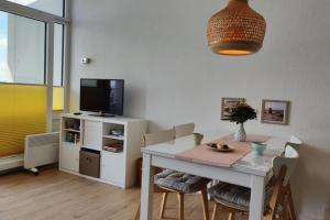 une salle à manger avec une table blanche et une télévision dans l'établissement Inselblume 59 - Moderne Ferienwohnung mit Meerblick, à Burgtiefe auf Fehmarn 