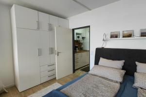 - une chambre avec des placards blancs, un lit et un miroir dans l'établissement Inselblume 59 - Moderne Ferienwohnung mit Meerblick, à Burgtiefe auf Fehmarn 