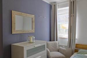 a bedroom with a mirror and a chair and a window at Inselblume 35 - Moderne Ferienwohnung in Neue Tiefe in Neue Tiefe Fehmarn