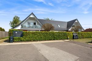 a house with a hedge in front of a house at Inselblume 35 - Moderne Ferienwohnung in Neue Tiefe in Neue Tiefe Fehmarn