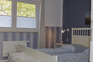 a bedroom with a bed and two windows at Inselblume 36 - Schöne Ferienwohnung in Neue Tiefe in Neue Tiefe Fehmarn
