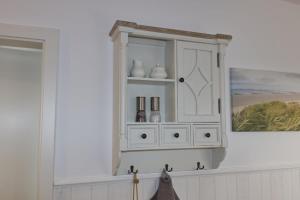 a white cabinet with vases on it in a room at Inselblume 36 - Schöne Ferienwohnung in Neue Tiefe in Neue Tiefe Fehmarn