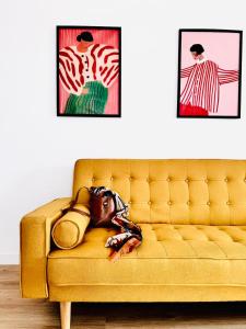 a yellow couch in a living room with two pictures at La Mansarda di Stella in Rieti