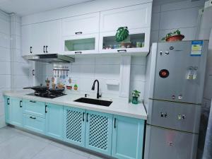 a kitchen with blue cabinets and a stainless steel refrigerator at Figo's Family Youth Hostel in Harbin +23 photos
