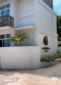 a white building with a palm tree in front of it at The Palm Ray Rasdhoo in Rasdu