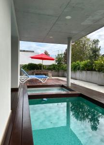 a swimming pool in a house with a red umbrella at Villas Vairocana in Santillana del Mar