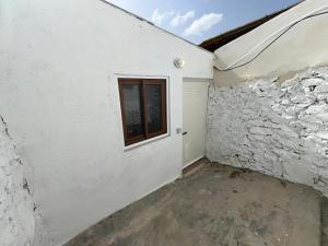 a white building with a window and a door at Alojamiento La Cartera I Alto del Garruchal in El Caracolero