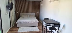 a small bedroom with a bed and a table and chairs at הבקתות של מאי in Ẕomeẖa