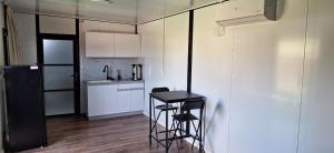 a small kitchen with a stool and a table in it at הבקתות של מאי in Ẕomeẖa