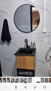 a bathroom with a sink and a mirror at הבקתות של מאי 