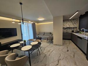 Una sala de estar con mesas y sillas y una cocina. en Ethereal Residences Nafplio 1, en Nauplia