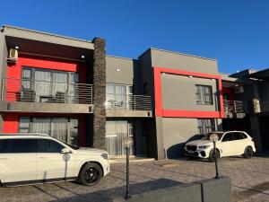 Dos coches blancos estacionados frente a un edificio en Mountain Top Luxury Villas, en Mbabane
