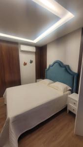 a bedroom with a large bed with a blue headboard at Hospedaria Alpina in Treze Tílias