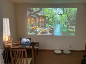 Ein Laptop auf einem Schreibtisch in einem Zimmer mit einem Gemälde an der Wand in der Unterkunft Ayaka House Hirai in Tokio