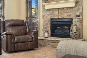 a living room with a leather chair and a fireplace at Stonebridge Hideaway - For 6 in Branson West +18 photos