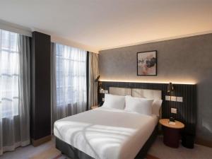 a bedroom with a large white bed and a window at The Sebel Sydney Martin Place in Sydney