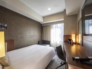 a hotel room with a bed and a desk and a window at ibis Styles Tokyo Ginza in Tokyo