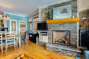 a living room with a stone fireplace and a dining room at Aspens 4607 in Big White