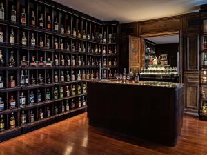 un bar avec beaucoup de bouteilles d'alcool dans l'établissement Domaine de la Reine Margot Paris-Issy - MGallery Collection, à Issy-les-Moulineaux