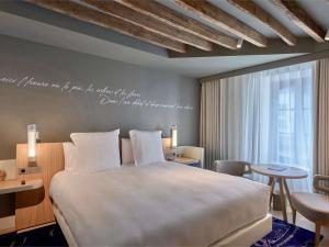 une chambre avec un lit et une écriture sur le mur dans l'établissement Domaine de la Reine Margot Paris-Issy - MGallery Collection, à Issy-les-Moulineaux