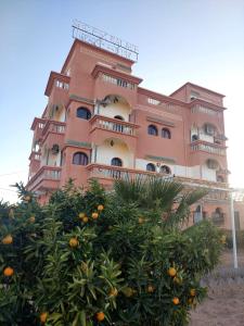 ein rosa Gebäude mit einem Orangenbaum davor in der Unterkunft SUD-EST palace in Aït Igad