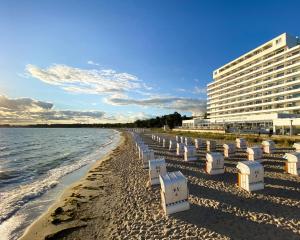 a row of chairs on a beach next to a hotel at Grand Hotel Seeschlösschen Sea Retreat & SPA in Timmendorfer Strand