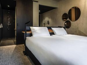een slaapkamer met een groot wit bed en een spiegel bij Hotel Valkenburg by Mercure - Next to Shimano Experience Center in Valkenburg +97 foto's