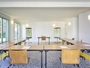 a classroom with tables and chairs in a room at Greet Hotel Versailles - Voisins Le Bretonneux in Voisins-le-Bretonneux