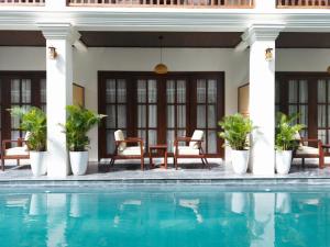 a pool in front of a house with chairs and a table at The Secret Luang Prabang in Luang Prabang