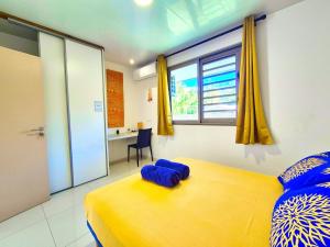 a bedroom with a yellow bed and a desk at Un écrin de paix au soleil et proche de la mer in Moorea