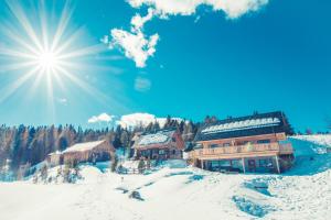 a ski lodge in the snow with the sun in the sky at Gasthaus Rieglerhütte in Sankt Lorenzen ob Murau