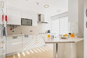 a white kitchen with white cabinets and a table at Fórum Glam 5B by Homie in Ilhéu do Gorgulho +22 photos