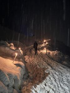 un homme marchant sur un chemin couvert de neige la nuit dans l'établissement Heimat - Das Natur Resort, à Prägraten am Großvenediger
